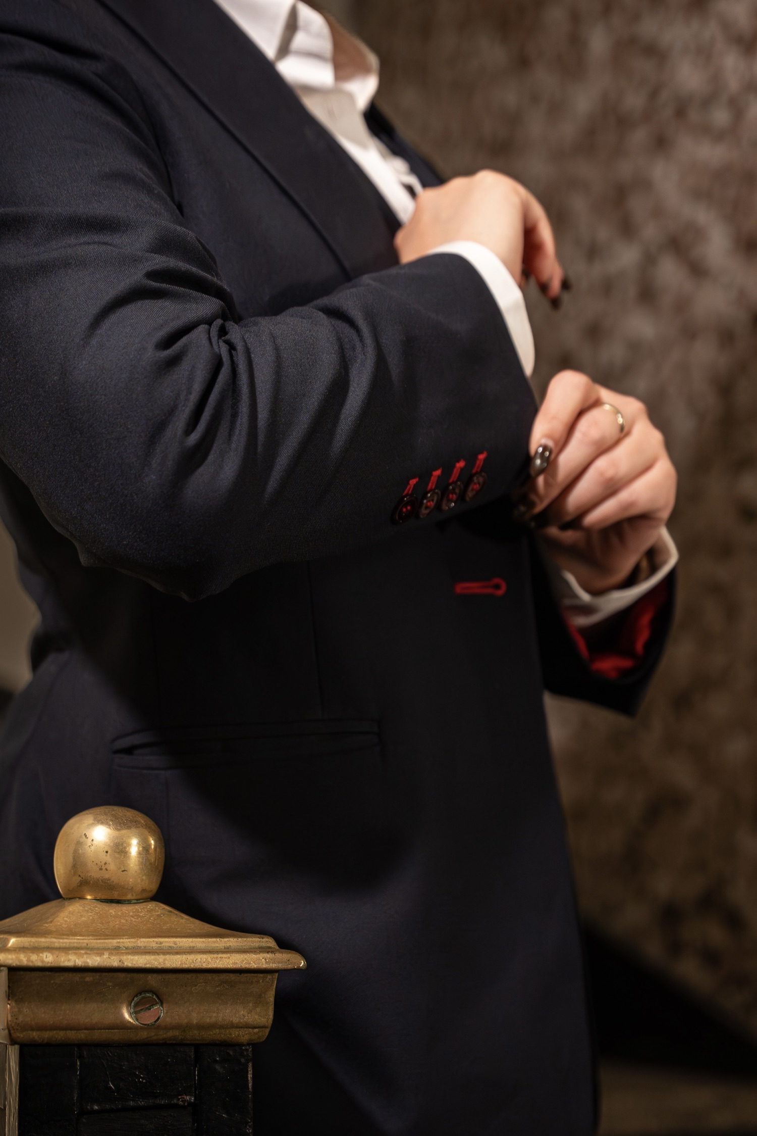 Red working buttonholes on a navy jacket cuff.