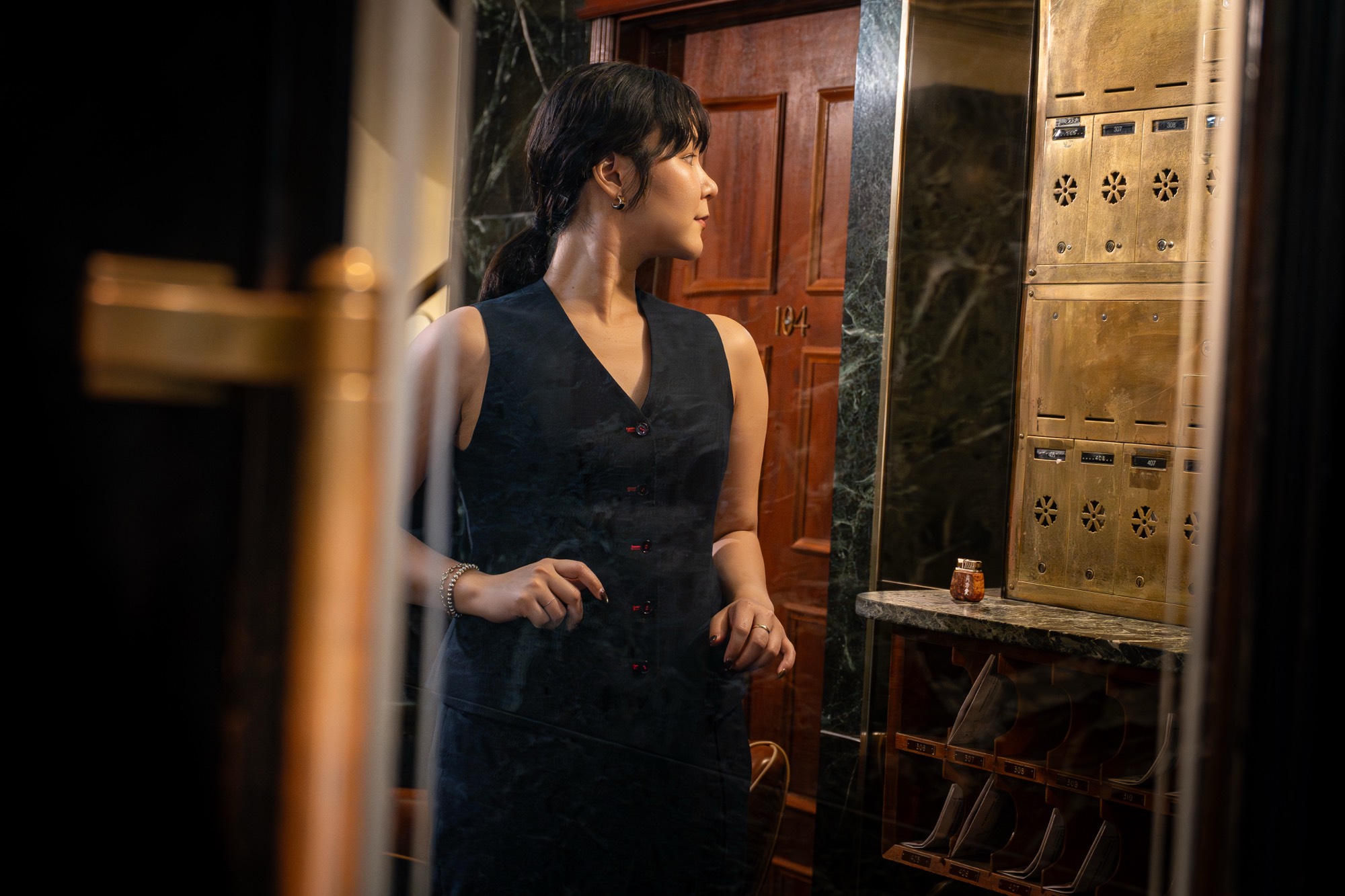 A dark jacquard waistcoat with red buttons, worn in a brass-and-marble lobby.
