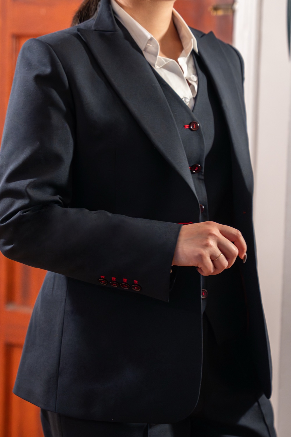 Navy jacket lapel with red working buttonholes over a waistcoat.